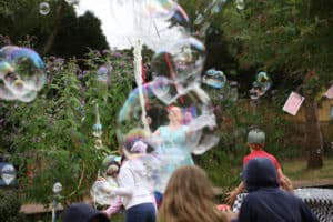 Childrens bubble entertainer making bubbles for the kids playing.