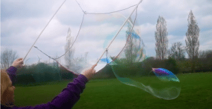 1 person kid inside a bubble wand making giant bubbles outdoors