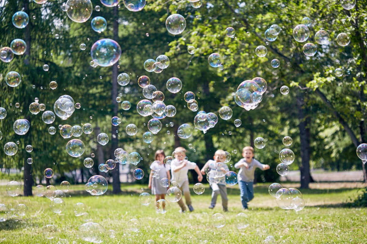 Children chasing lots of giant bubbles at a party in Stroud