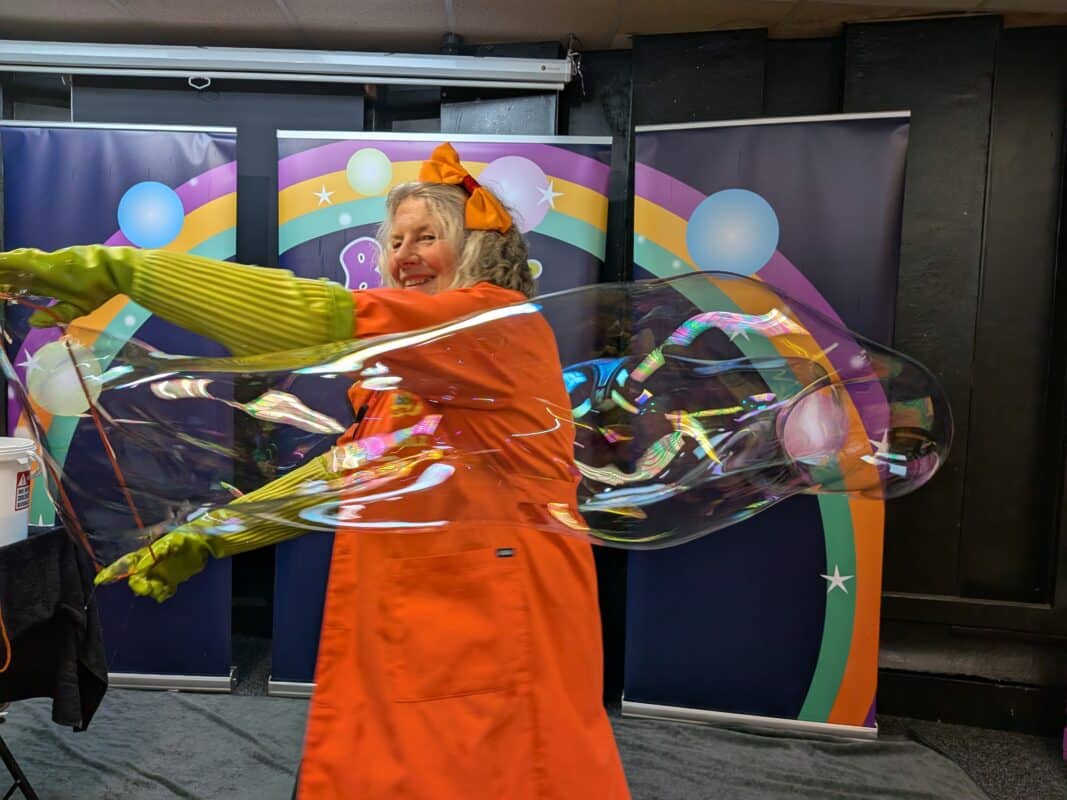 Bubble performer making a giant bubble and teaching how